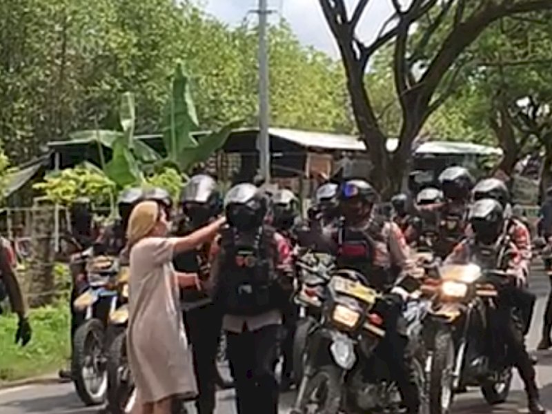 Seorang emak-emak berdaster warna karamel turun ke jalan, mengadang personel bersenjata yang memenuhi jalan. Kejadian terekam di jalan poros Takalar, tepatnya di Desa Aeng Towa, Kecamatan Galesong Utara, Takalar, Selasa (15/11/2022).