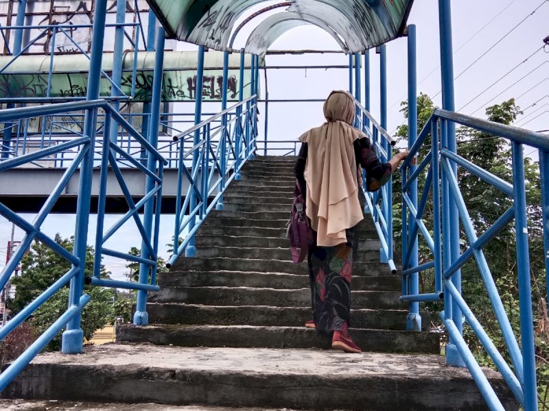 Seorang pengguna JPO di depan M'Tos, Jl. Perintis Kemerdekaan, Kecamatan Tamalanrea, Kota Makassar, Jum'at (25/11/2022). (Foto: Samsir)