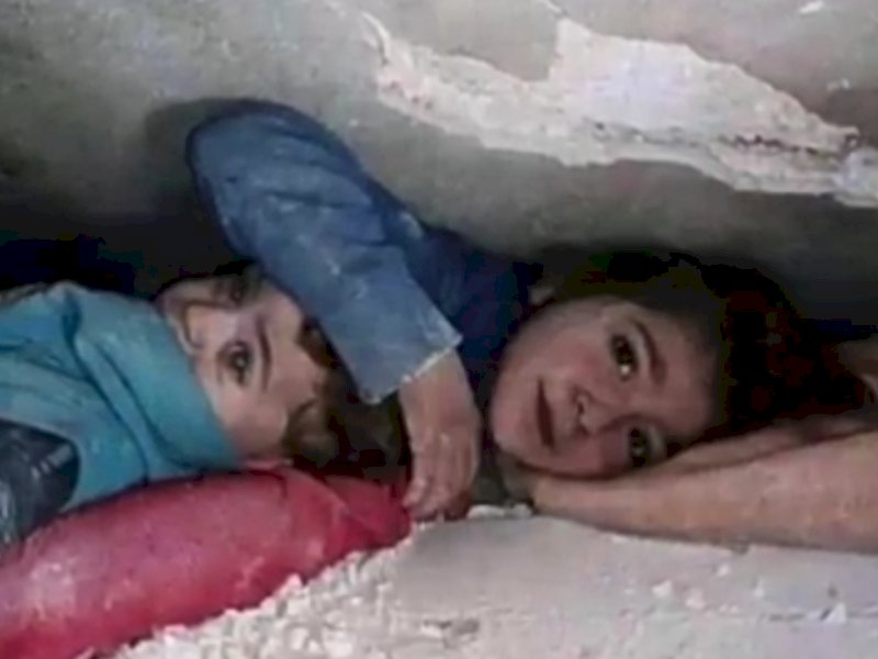 Bocah perempuan lindungi adiknya di bawah reruntuhan gempa di Suriah. Keduanya selamat setelah tertimbun reruntuhan selama 17 jam. Atau sejak gempa bumi magnitudo 7,8 yang berpusat di tenggara Turki, Kota Gaziantep dan Provinsi Kahramanmaras, Senin 6 Februari 2023 subuh waktu setempat. (Ist).