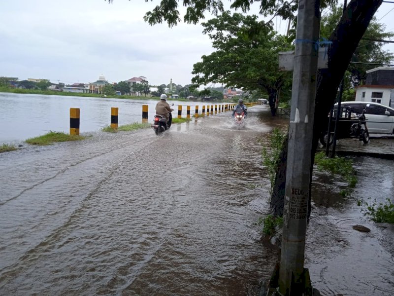 Luapan Waduk Tunggu Pampang di Kecamatan Manggala, kota Makassar, masih merendam sebagian badan jalan bantaran waduk, Sabtu (18/2/2023) pagi. (Ikbal Nur/jejakfakta).