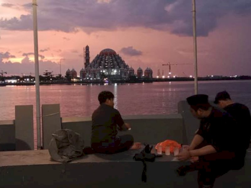 Pengunjung Pantai Losari Makassar menikmati senja di balik Masjid 99 Kubah sambil berbuka puasa. @Jejakfakta/Samsir