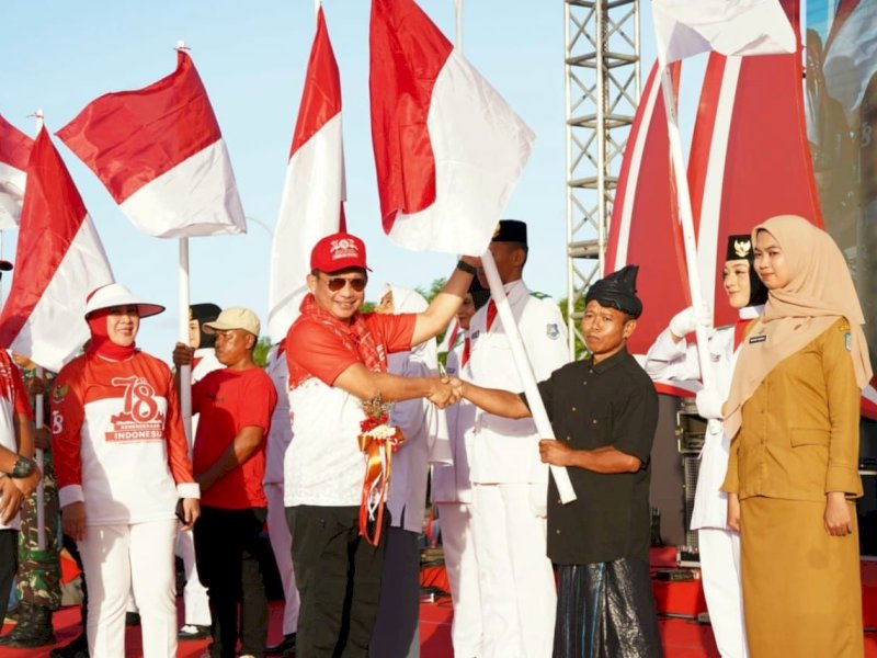 Mendagri Tito Karnavian  membagikan bendera dalam Gerakan Nasional Pembagian 10 juta Bendera Merah Putih di lapangan hitam pantai Bira Bulukumba, Jumat (11/8/2023). @Jejakfakta/dok. Humas Pemkab Bulukumba