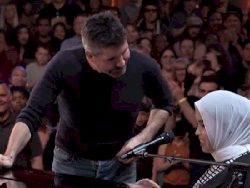 Produser musik dan juri acara pencarian bakat terkenal America's Got Talent, Simon Cowell, menghampiri Putri Ariani dan meminta Putri menyanyikan sebuah lagu lagi sebelum memberikan Golden Buzzer. (foto tangkapan layar).