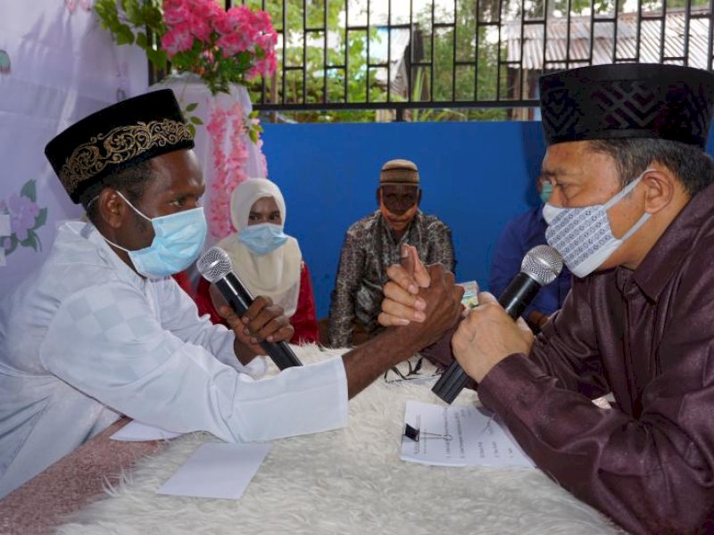 ANTARA/Olha Mulalinda
Petugas pencatat nikah Kantor Urusan Agama (KUA) sekaligus penghulu (kanan) melakukan proses Ijab Kabul terhadap pasangan pengantin di Kota Sorong, Papua Barat, Ahad (18/10/2020). Sebanyak 10 pasang calon pengantin muslim asli Papua mengikuti kegiatan nikah massal yang digelar oleh Yayasan Sahabat Muda Adi Yasa (SMAY) dengan tetap mengikuti protokol kesehatan di tengah pandemi COVID-19. 