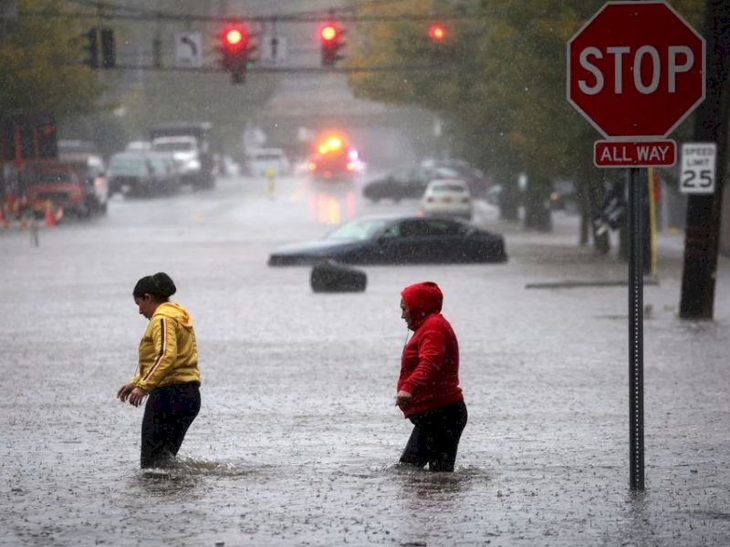 Warga berjalan melewati di tengah banjir dan hujan lebat di Mamaroneck pinggiran Kota New York, Westchester County, New York, Amerika Serikat, Jumat 29 September. (REUTERS/Mike Segar).