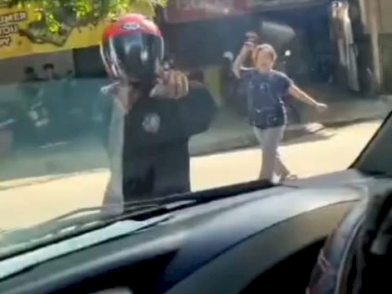 Tangkapan layar seorang pemotor menahan mobil Dinas Sosial Kota Makassar secara paksa. Kemudian terlihat seorang ibu-ibu marah-marah dan memukul ibu tersebut. @Jejakfakta/Tangkapan Layar 