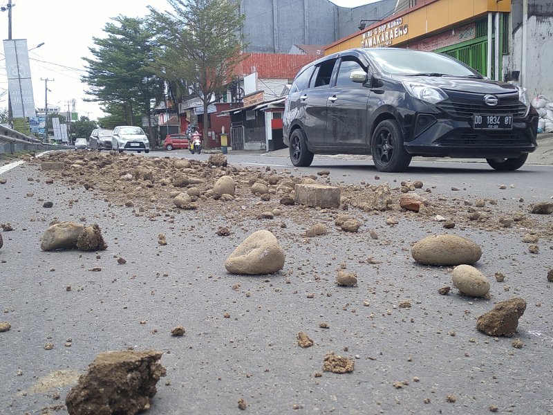 Material batu dan tanah berserakan dan menutup sebagian badan jalan  Jl. Pengayoman Makassar, Kamis (14/3/2024). @Jejakfakta/Nurdin Amir