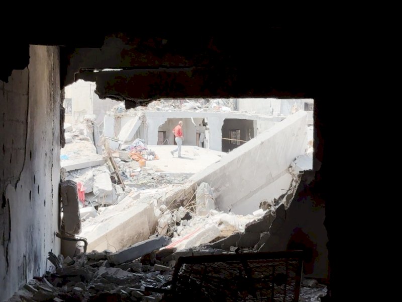 Seorang laki laki berjalan melewati puing-puing di Khan Younis. @Jejakfakta/dok. Save the Children