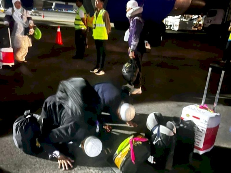 Jemaah haji kloter 7 asal Sulawesi Barat (Sulbar) sujud syukur saat mendarat dengan selamat di Bandara Internasional Sultan Hasanuddin Makassar pada Jum'at (28/6/2024). @Jejakfakta/dok. Humas Kemenag