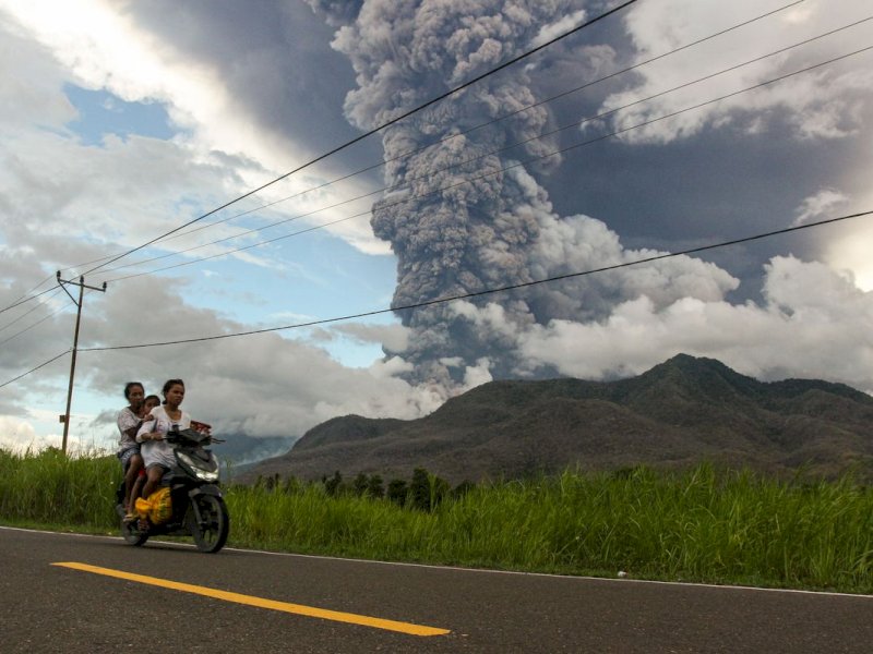 Warga mengendarai sepeda motor dengan latar belakang erupsi Gunung Lewotobi Laki-laki di Desa Konga, Kecamatan Titehena, Kabupaten Flores Timur, Provinsi Nusa Tenggara Timur, Kamis (7/11/2024). PVMBG menyatakan Gunung Lewotobi Laki-laki kembali erupsi pada Kamis (7/11) pukul 10.48 WITA dengan tinggi kolom abu teramati 5.000 m di atas puncak. ANTARA FOTO/Mega Tokan/sgd/tom.(ANTARA FOTO/Mega Tokan)