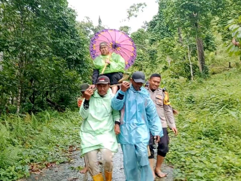 Seorang lansia bernama Muhammad Siri (78 tahun) waga asal Dusun Pusedana, Desa Tapua, Kecamatan Matangga, Kabupaten Polewali Mandar (Polman), Sulawesi Barat, terpaksa ditandu menuju pusat pelayanan kesehatan, karena akses jalan rusak, Senin (23/12/2024). @Jejakfakta/Istimewa