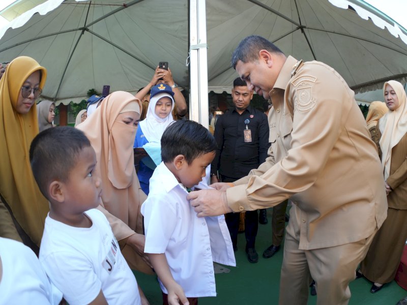 Wali Kota Makassar Munafri Arifuddin, secara simbolis memasangkan baju seragam sekolah gratis bagi siswa baru tingkat Sekolah Dasar (SD), di SD Lariang Bangi, Senin (21/7/2025). @Jejakfakta/dok. Humas Pemkot Makassar